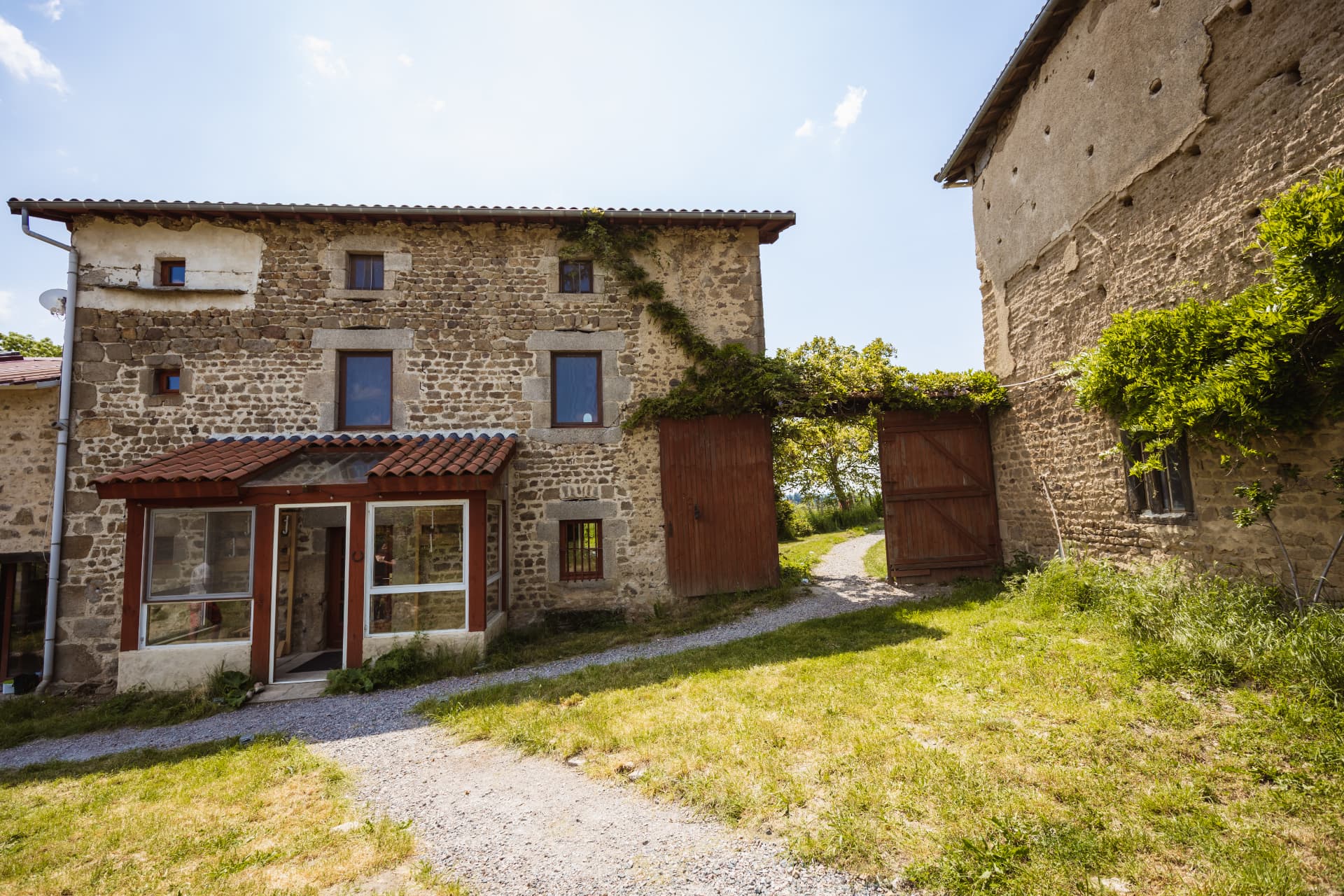 Façade en pierre et cour gravillonnée du gîte