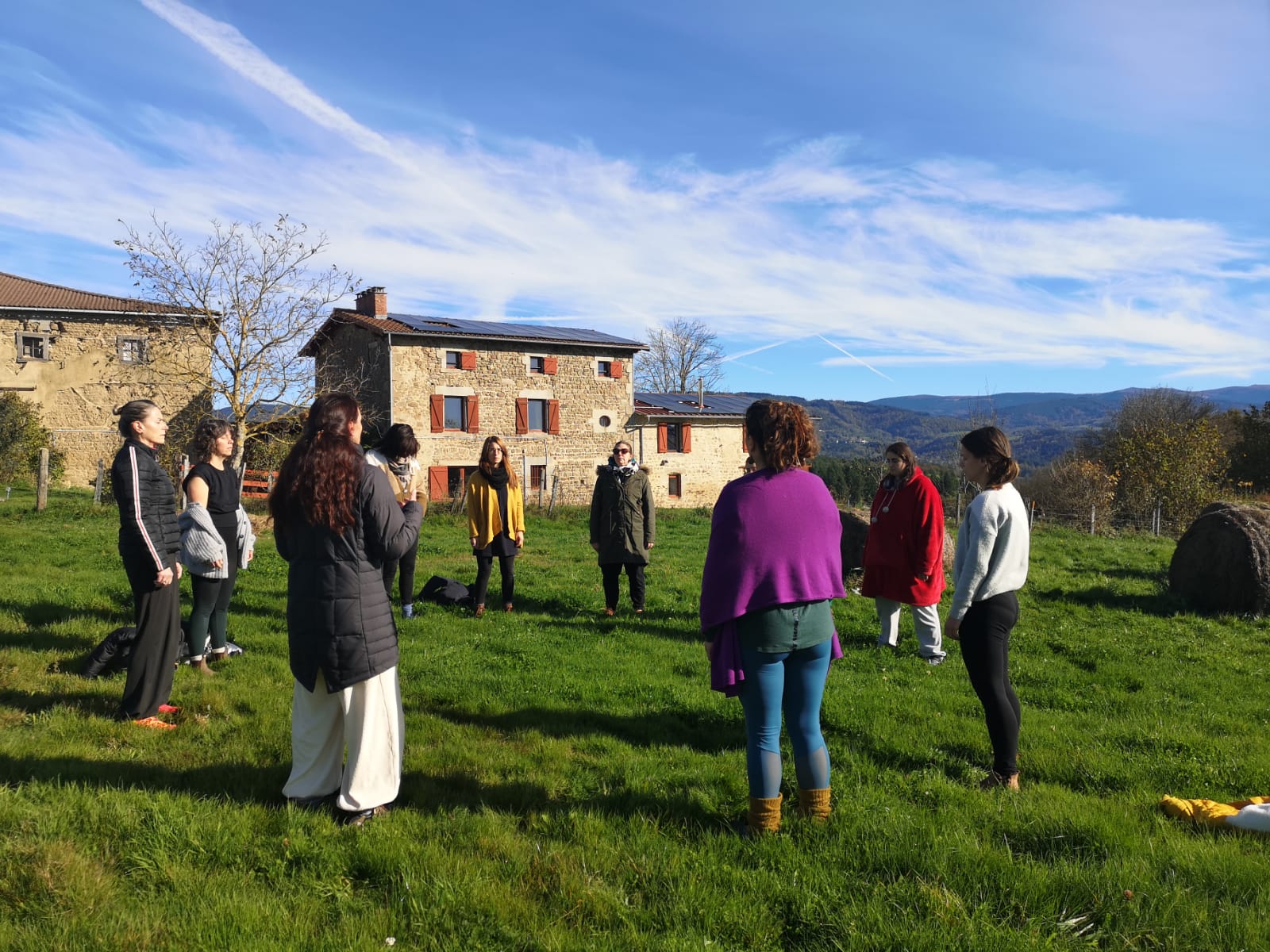 Groupe en cercle devant la ferme en pierre lors d'un séminaire