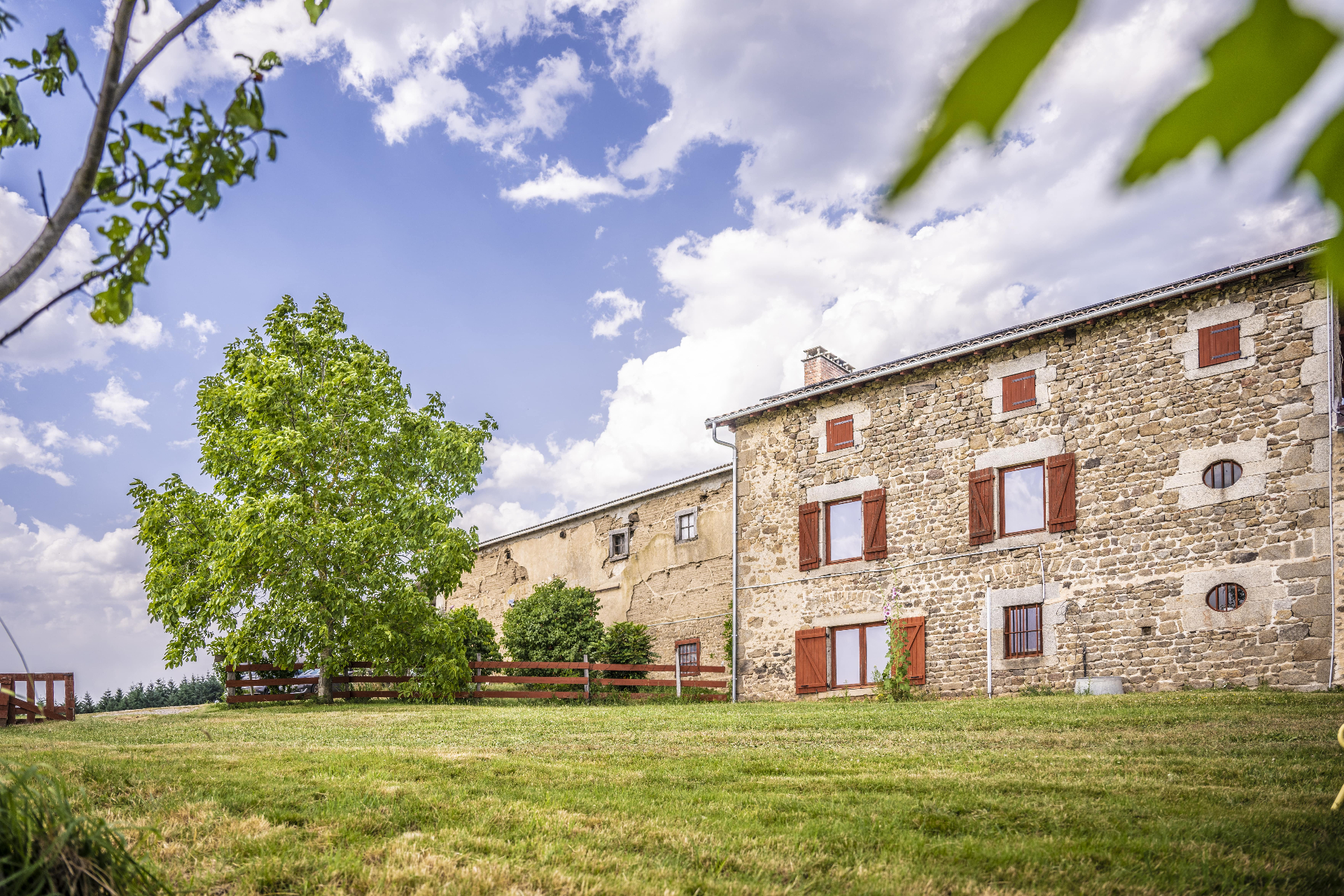 Façade en pierre du gîte sous un ciel d'été