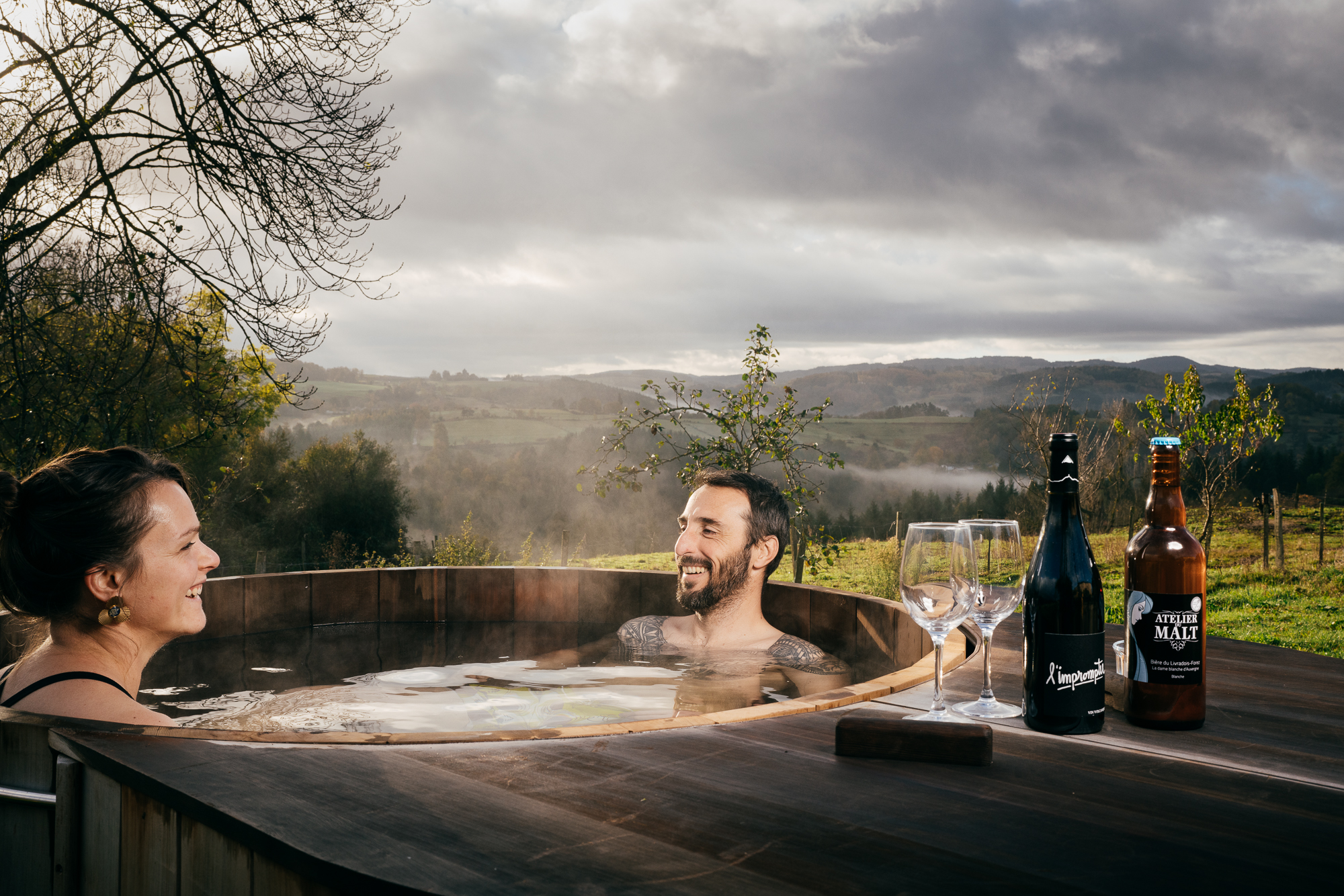 Couple dans le bain nordique face aux collines brumeuses