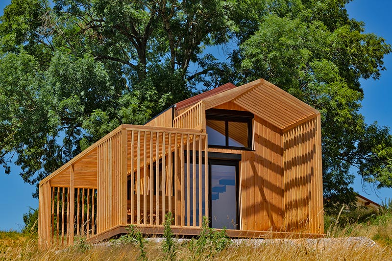 Façade en bois du COQhome sous les grands arbres